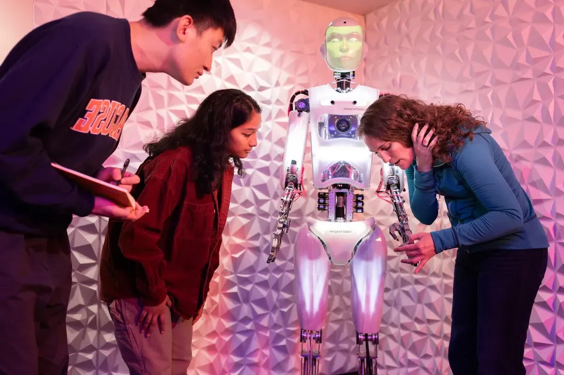 Student with professor looking at a robot.